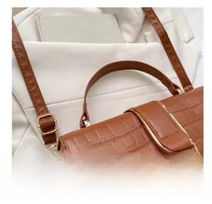Detailed close-up of brown crocodile pattern leather handbag with gold metal clasp