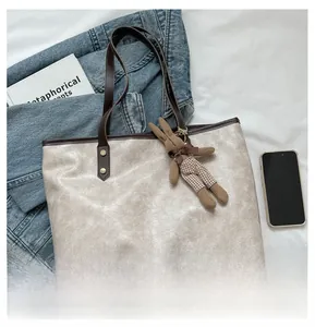 Detail of off-white faux leather tote bag with vintage texture and plush rabbit charm