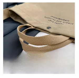 Detail of woven khaki canvas bag handles with high-density texture and metal snap button
