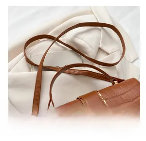 Close-up of brown crocodile pattern handbag with gold hardware and shoulder strap details