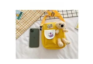 Détail du sac bandoulière en toile jaune avec broderie cupcake et breloque ours en peluche