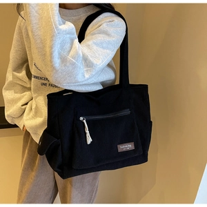 Detail of black corduroy bucket bag showing textured stripes and side flap pocket design