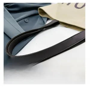 Gros plan détaillé de la poignée en similicuir marron et du sac en toile avec lettres