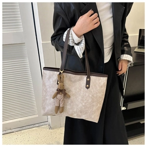 Detail of light beige matte bucket bag with dark brown handles and cute rabbit charm