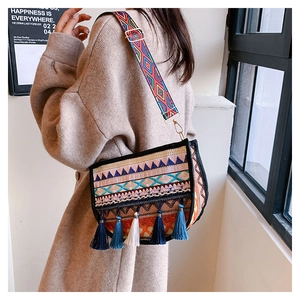 Detail of bohemian woven crossbody bag featuring colorful patterns and blue-white tassels