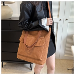 Brown corduroy tote bag with front pocket and adjustable strap worn by model