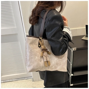 Side view of large grey tote bag with brown leather handles and a cute rabbit charm