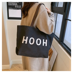 Détail du sac cabas en toile noire avec lettres HOOH et bandoulières en similicuir brun