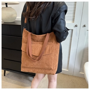Brown corduroy tote bag showing large front pocket and adjustable shoulder strap detail