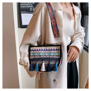 Ethnic embroidered crossbody bag featuring colorful tassels and wide woven shoulder strap