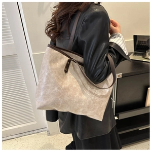 Detail view of the beige bucket tote bag featuring dark brown straps and textured finish