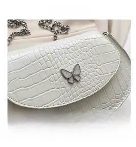 Macro shot of white crocodile texture mini saddle bag with silver butterfly buckle