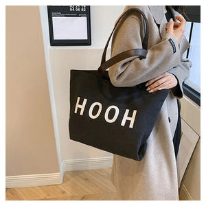 Détail du sac cabas en toile noire avec lettrage HOOH blanc et anses en cuir marron