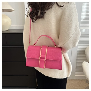 Detailed view of magenta crocodile pattern handbag with gold hardware on a model