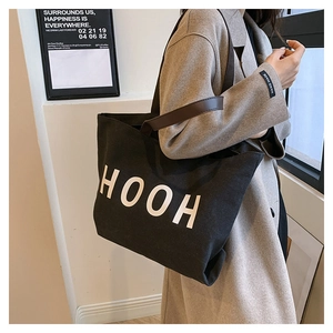 Sac fourre-tout noir en toile avec imprimé HOOH porté par un mannequin