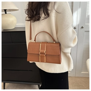 Detail of caramel brown faux crocodile leather crossbody bag with gold metal buckle closure
