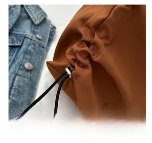 Détail de la texture en nylon marron de qualité et fermeture par cordon noir sur le grand sac