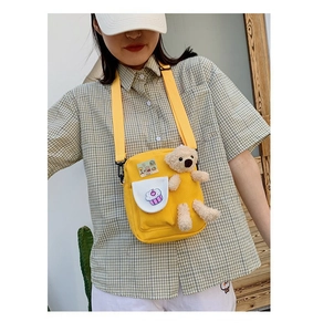 Détail du sac bandoulière en toile jaune avec broderie cupcake et breloque ourson mignon