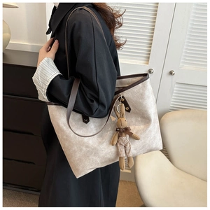 Detail view of large tote bag with brown leather handles and cute bunny plush charm