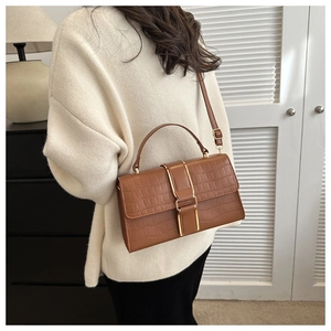 Close-up of caramel brown faux crocodile pattern shoulder bag with metallic buckle detail