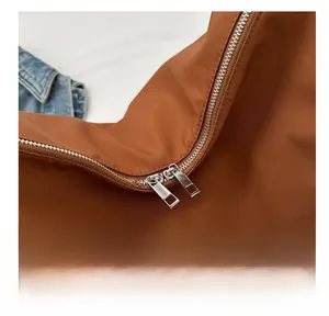 Vue détaillée des doubles fermetures éclair en argent sur un sac en nylon marron