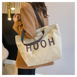 Détail d'un sac cabas en toile beige avec imprimé HOOH et anses marron foncé