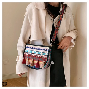 Close-up of ethnic style embroidery and colorful tassels on a boho crossbody bag