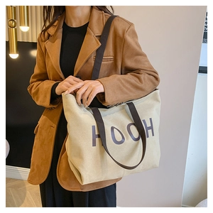 Gros plan du sac fourre-tout en toile beige avec lettrage HOOH et anses marron foncé