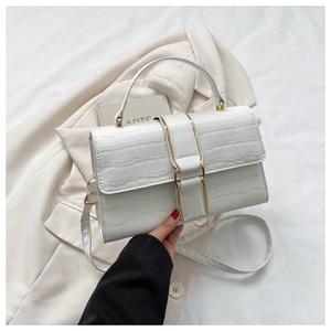 Detail of white crocodile pattern leather bag with golden metal buckle and top handle