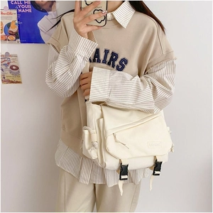 Detail of off-white canvas messenger bag with buckle closure and side pocket for daily use