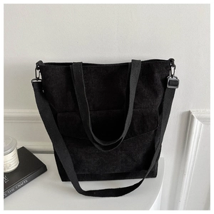 Detail of black corduroy tote bag showing texture, front flap pocket and shoulder strap