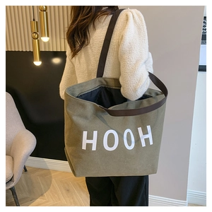Grand sac cabas en toile vert olive avec imprimé HOOH porté à l'épaule par un mannequin