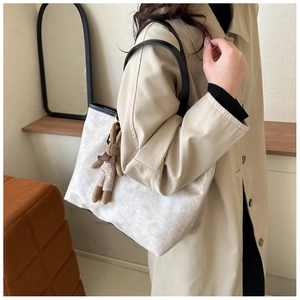 Detail of minimalist beige tote bag with a cute plaid rabbit plush pendant