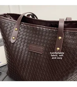 Detail of dark brown woven tote bag featuring golden rivets and fashion leather label
