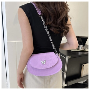 Model wearing light purple crocodile embossed saddle bag with butterfly buckle and silver chain