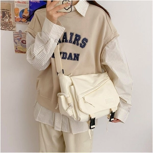 Detail of cream canvas messenger bag with large capacity pockets and fashion label