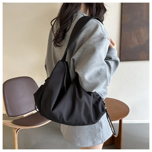 Détail du sac à bandoulière plissé en nylon noir montrant la texture et la grande capacité