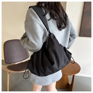 Vue détaillée d'un sac à bandoulière en nylon noir avec cordon porté par un mannequin en studio