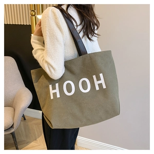 Détail du grand sac cabas en toile vert armée avec anses en cuir marron et texte HOOH