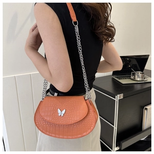 Detail view of orange crocodile pattern mini saddle bag with silver butterfly clasp