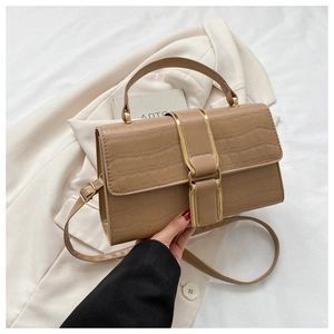 Detail of light brown crocodile embossed handbag with stylish gold trim and buckle closure