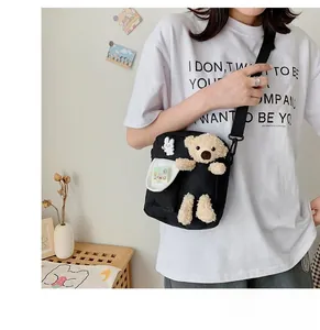 Détail du sac bandoulière en toile noire avec ours en peluche 3D et badges lapin mignons