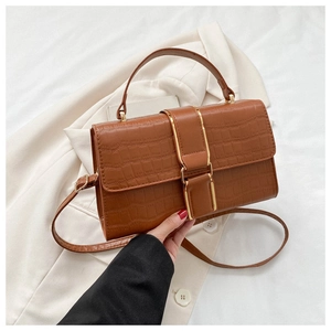 Detailed close-up of brown crocodile pattern handbag with golden metal buckle clasp