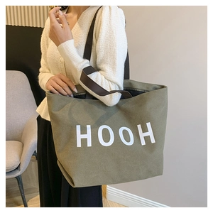 Grand sac cabas en toile vert olive avec imprimé HOOH porté par un mannequin