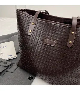 Detail of dark brown woven leather tote bag with FASHION leather tag and gold rivets