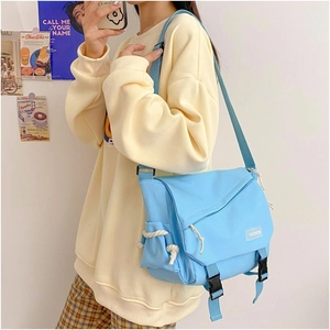 Close-up of light blue canvas messenger bag featuring buckle closure and woven rope detail