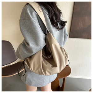 Vue détaillée de la texture plissée et de la large bandoulière du sac en nylon kaki