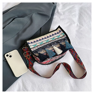 Detail of bohemian crossbody bag with colorful tassels and wide patterned shoulder strap
