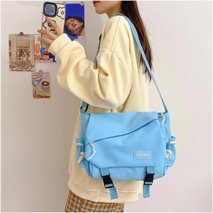 Detail view of the light blue canvas messenger bag featuring a Fashion label on the flap