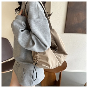 Détail du sac cabas en nylon beige montrant les cordons latéraux et la fermeture éclair